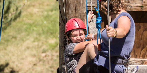 Two girls completing a recreational therapy task on top of the ropes course at New Haven Residential Treatment Center