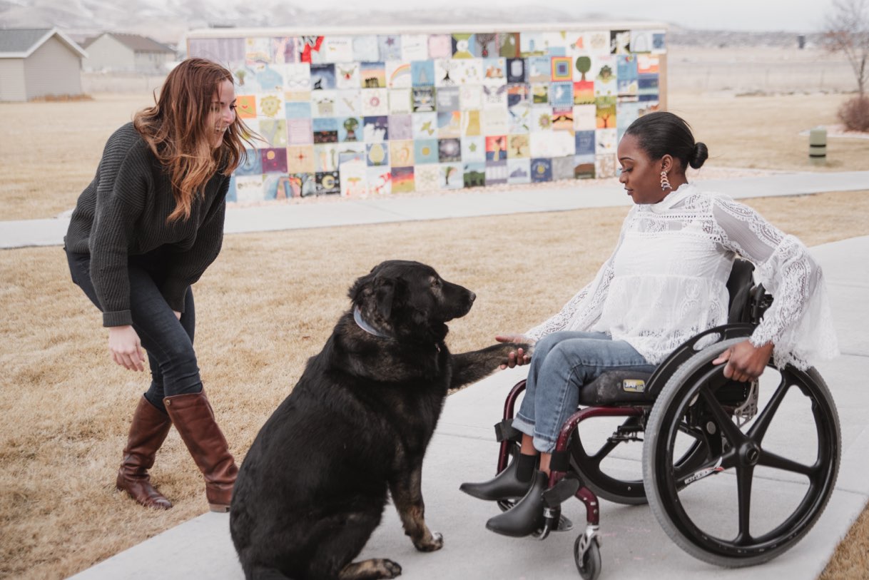 Two girls with a dog by the art wall outdoors at the Saratoga Springs campus, New Haven Residential Treatment Center